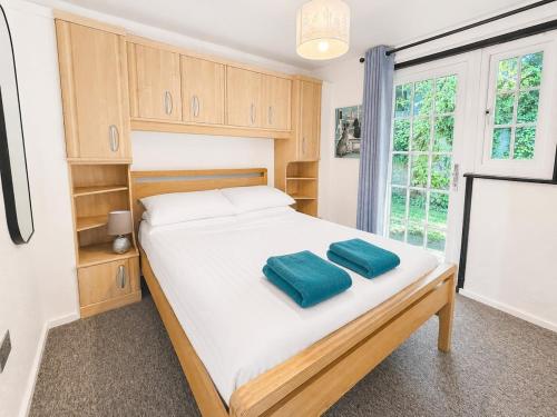 a bedroom with a bed with two blue pillows on it at Cornwall Cosy Bungalow in Hayle