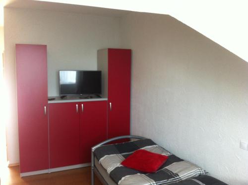 a bedroom with red cabinets and a flat screen tv at Landgasthof Hegau in Dunaszekcső