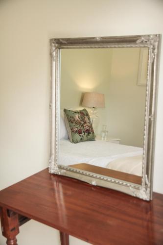 a mirror on a table with a bed in a room at Olive Manor Guest House in Newcastle