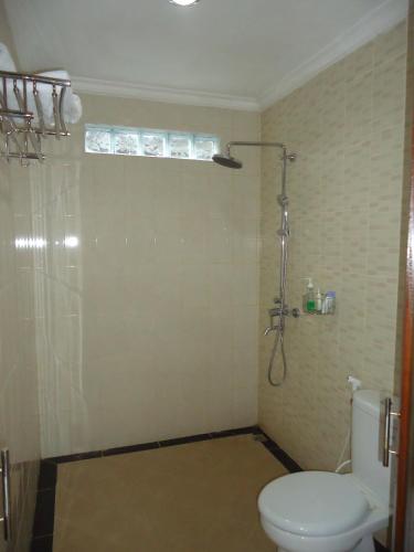 a bathroom with a white toilet and a shower at Dewa Put Guest House in Ubud
