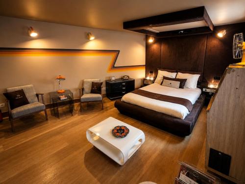 a hotel room with a bed and a desk and chairs at Chez Claude - Retro Chic Suite in Charleroi