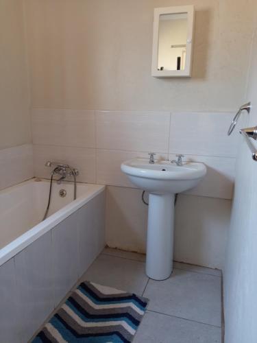 a white bathroom with a sink and a bath tub at Benema's Rest in Waterval Boven