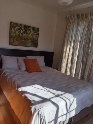 a bedroom with a large bed with white sheets at Benema's Rest in Waterval Boven