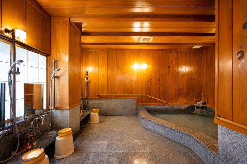 a bathroom with a bath tub and wooden walls at Ryokan Asunaro in Takayama
