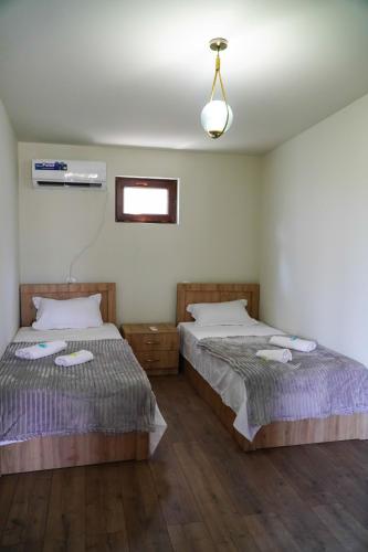 a bedroom with two beds and a window and a fan at NIISS house in Akhaltsikhe