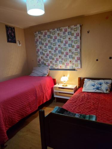a bedroom with two beds with red sheets and a window at Casa Labranza estacionamiento 2 dormitorios amoblada Jorge Alessandri 0979 in Temuco