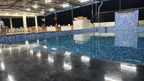 a swimming pool with blue tiles on the floor at Neem Tree Farm Stay in Ujjain