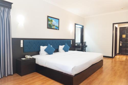 ein Schlafzimmer mit einem großen weißen Bett und blauen Kissen in der Unterkunft Royal Hotel Saigon in Ho-Chi-Minh-Stadt