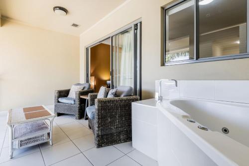 a bathroom with a tub and two chairs at Lagoons Resort Studio 64 in Agnes Water