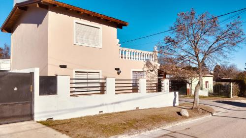 a white house with a white fence and a tree at Mí cielo in Huerta Grande