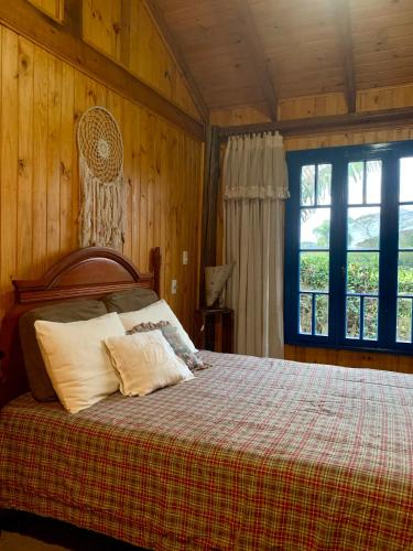 a bedroom with a bed with a plaid blanket and a window at Casa de Campo in Guaíba