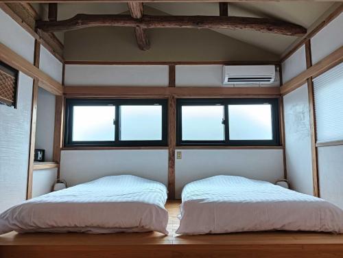 two beds in a room with two windows at 岩室久元 in Niigata
