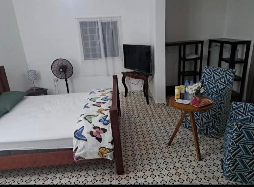 a bedroom with a bed and a table and a tv at butterfly lodge in Brufut