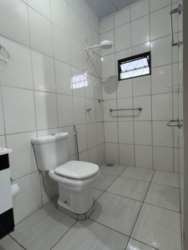 a white bathroom with a toilet and a shower at Refúgio Mix Pousada com 3 suítes e 9 camas in Vilhena