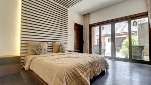 a bedroom with a large bed and a large window at Villa Maeni in Munggu