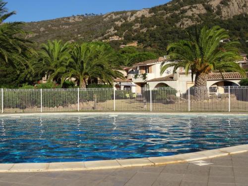 une piscine avec des palmiers et une clôture dans l'établissement Villa 8 au Village Marin, à Porto-Vecchio