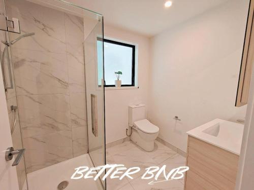 a bathroom with a shower and a toilet and a sink at Quiet Haven Retreat | Cozy Modern Townhouse in Lower Hutt