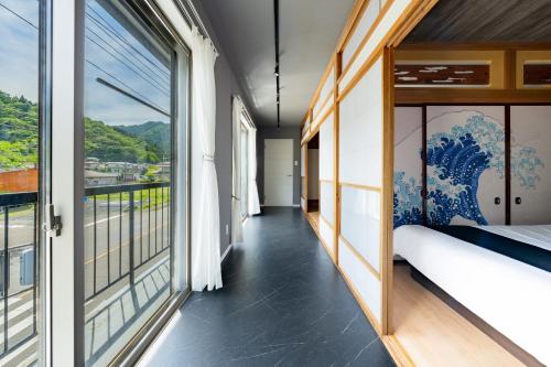 a room with a balcony with a bed and large windows at OZ nikko in Nikko
