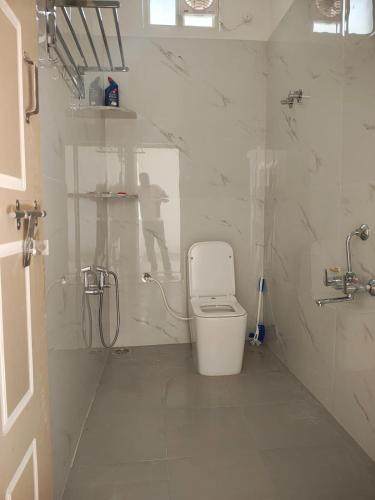 a white bathroom with a toilet and a shower at Tranquil Breeze Stay in Napoklu