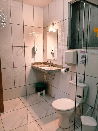 a bathroom with a toilet and a sink and a mirror at Pousada Alforria Lavras Novas centro in Lavras Novas