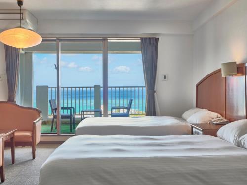 a hotel room with two beds and a balcony at 恩納マリンビューパレス in Onna