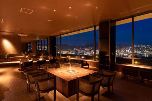 a restaurant with a table and chairs and a view at Ooedo Onsen Monogatari Premium Nagasaki Hotel Seifu in Nagasaki