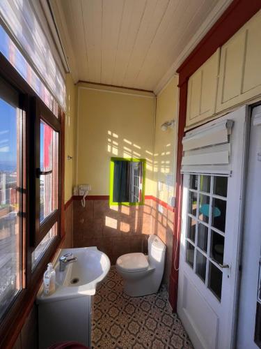 a bathroom with a white toilet and a sink at Amura Hostel in Puerto Varas
