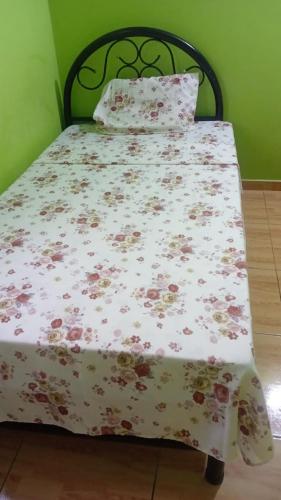 a bed with a floral bedspread and pillows on it at Hospedaje restaurant Sr de Sipan in Sipán
