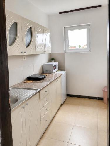 a kitchen with white cabinets and a sink and a window at Apartment Pasic in Petrovaradin