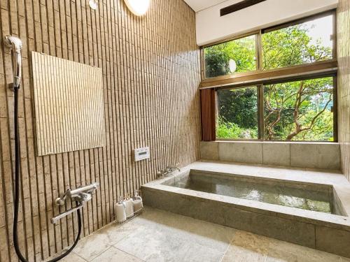 a bathroom with a bath tub and a window at 春まち in Ito