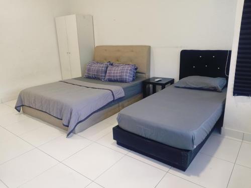 two beds sitting in a room with a white floor at F.A Guesthouse Pasir Gudang in Pasir Gudang