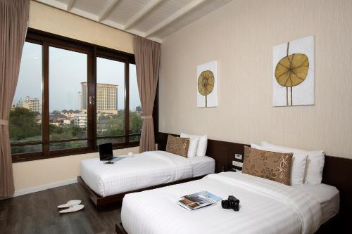 pokój hotelowy z dwoma łóżkami i oknem w obiekcie De Chai Colonial Hotel & Spa w mieście Chiang Mai