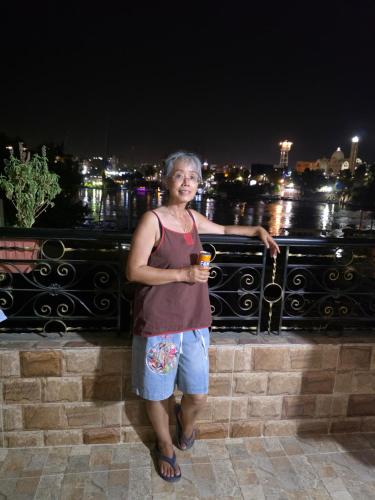 a woman standing on a fence with a drink in her hand at Bakar Nubian Guest House in Aswan
