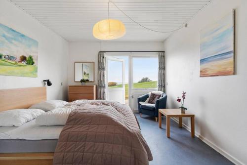 a bedroom with a bed and a chair and a window at Sct Knudsborg - 12E - Apartment on the beach in Brenderup