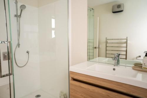 a white bathroom with a sink and a shower at Southern Peaks Hideaway in Queenstown Airport