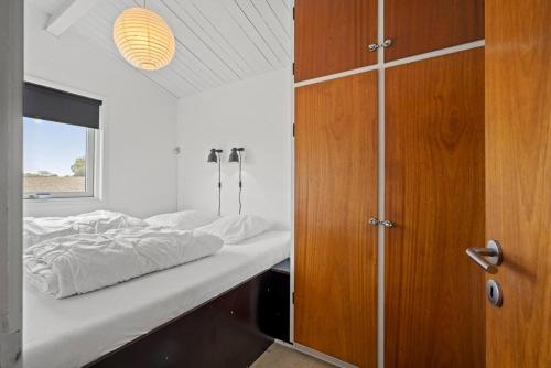 a bedroom with a bed and a wooden cabinet at Sct Knudsborg - 12J - Summerhouse on the beach in Brenderup