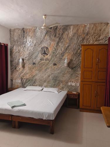 a bedroom with a bed and a stone wall at Dver Prirody in Kovalam