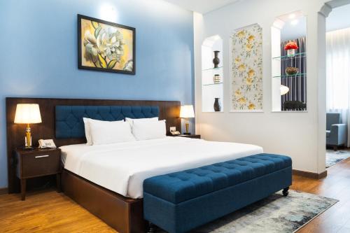 ein Schlafzimmer mit einem Bett und einer blauen Wand in der Unterkunft Royal Hotel Saigon in Ho-Chi-Minh-Stadt