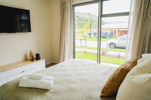 a bedroom with a bed with a large window at Southern Peaks - Private Room in Queenstown Airport