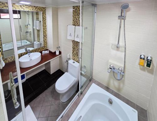 a bathroom with a toilet and a sink and a tub at Rashu Hiyaa Hotel in Dhiffushi
