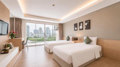 a hotel room with two beds and a large window at Olive Hotel & Residence Bangkok Sukhumvit 101 near True Digital Park in Bangkok