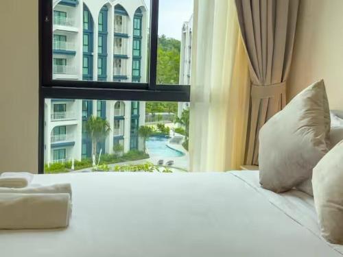 a bedroom with a large white bed and a window at Title Naiyang Walk To Beach C111 in Nai Yang Beach