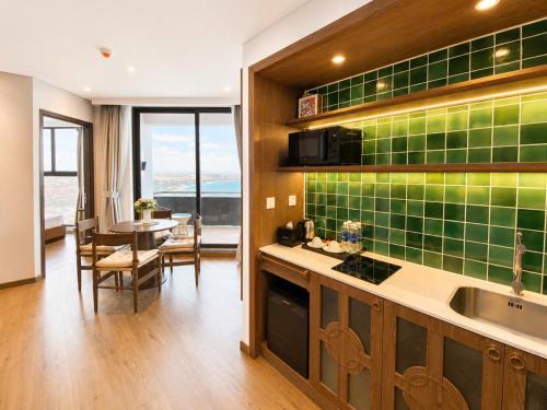 a kitchen with green tile on the wall and a table at Mandala Cham Bay Mũi Né in Mui Ne