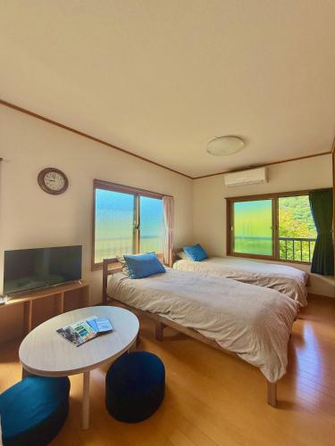 a bedroom with two beds and a table and a tv at Takumisou 2 in Kiso