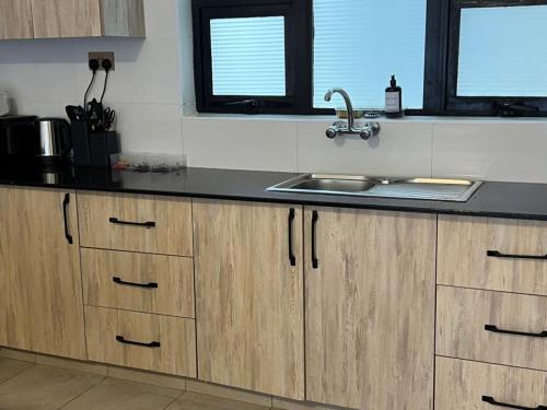 a kitchen with wooden cabinets and a sink at Serenity Residences 1BR Ruaka Near Two Rivers & UN Gigiri in Nairobi
