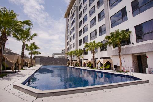 斗六的住宿－三好國際酒店，棕榈树建筑前的游泳池