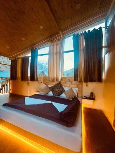 a bedroom with two beds and a large window at Kübes By The Raasta in Jispa
