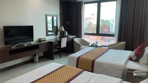 a hotel room with two beds and a desk and a television at Khách sạn Rosy in Hòa Ðình