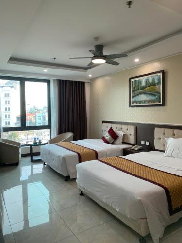 a hotel room with three beds and a ceiling fan at Khách sạn Rosy in Hòa Ðình