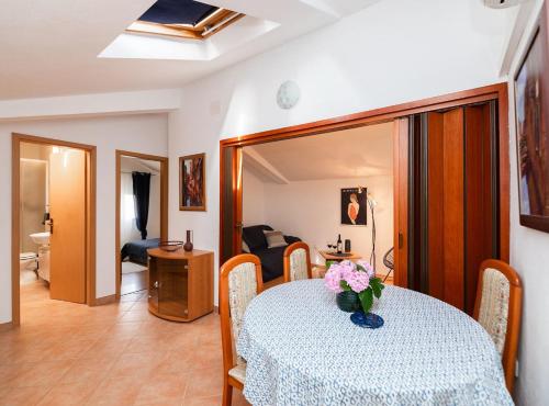 a dining room with a table with a vase of flowers on it at Apartments Roda in Supetar